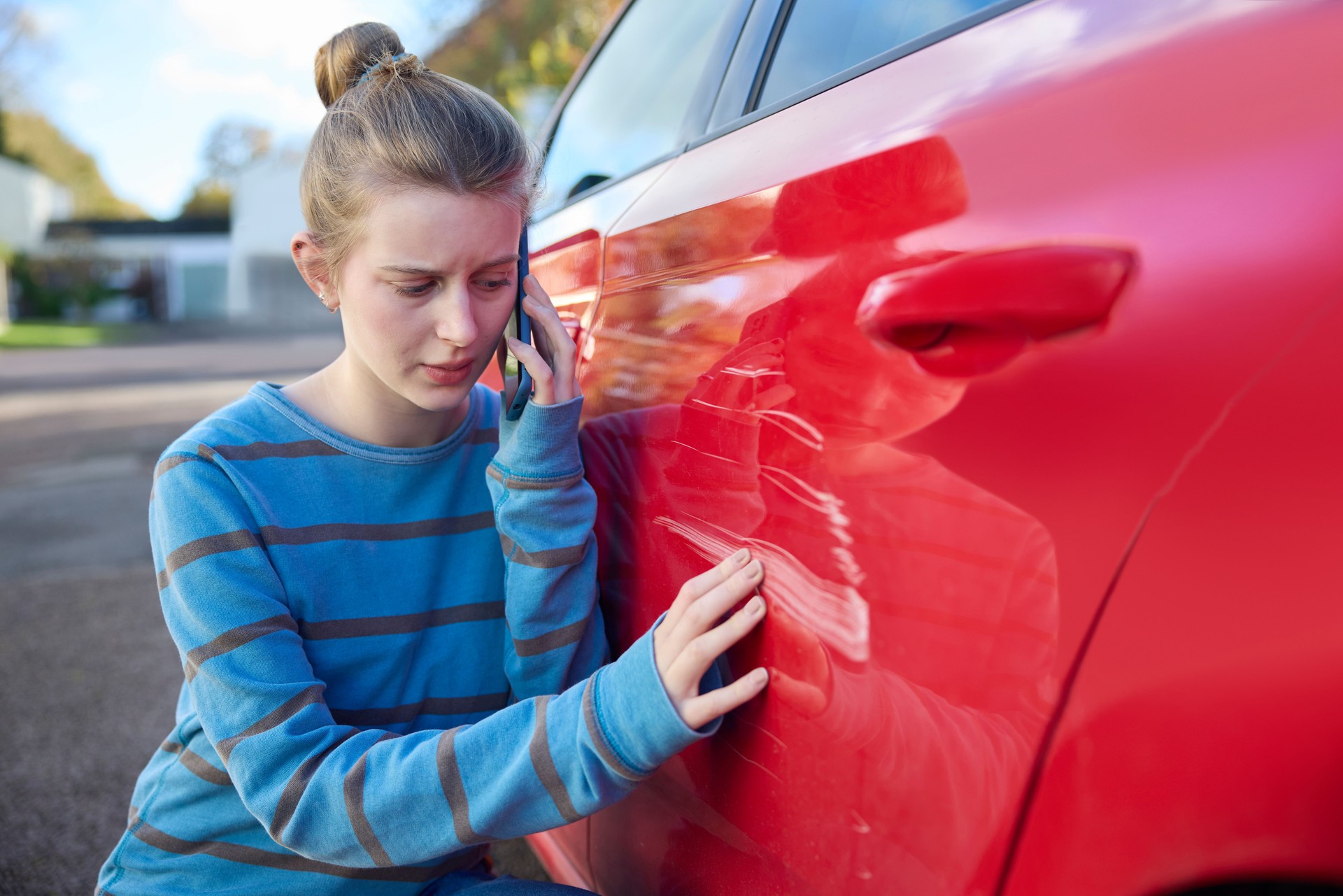 Young Worried Teenage Female Driver With Damaged Car After Accident Calling Insurance Company On Mobile Phone